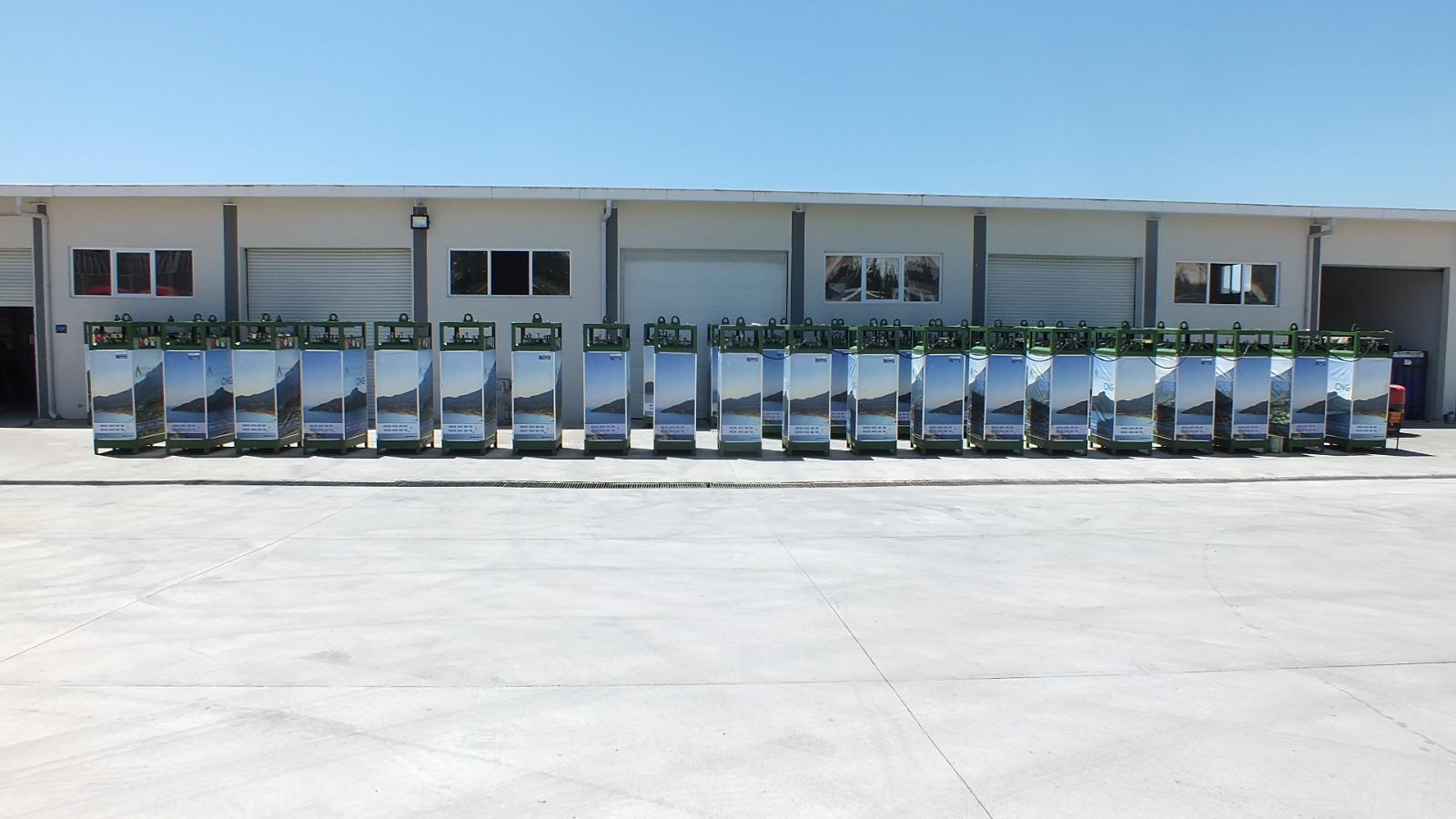 Long row of CNG dispensers with scenic branding outside industrial building