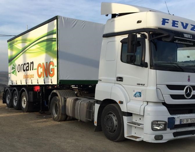 White Mercedes truck with Orcan branded green CNG trailer featuring flowing design elements